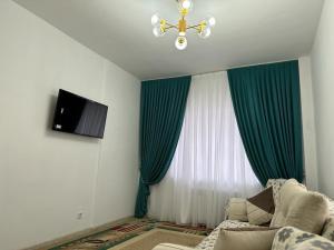 ein Wohnzimmer mit grünen Vorhängen und einem Kronleuchter in der Unterkunft Квартира in Türkistan