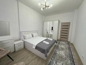 una camera da letto bianca con un letto e una televisione di Квартира a Türkistan
