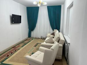 a living room with white furniture and blue curtains at Квартира in Türkistan