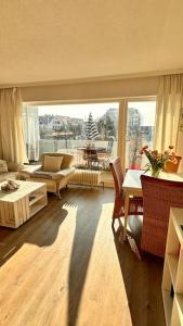 ein Wohnzimmer mit einem großen Fenster und ein Wohnzimmer mit einem Tisch in der Unterkunft LUV & LEE Waterkant Ferienwohnung SPO in Sankt Peter-Ording