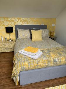 a bed with a yellow blanket and pillows on it at First floor Pad Carterton near Burford in Shilton