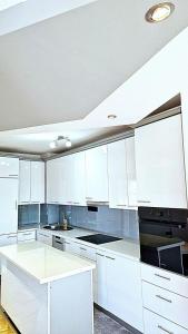 a white kitchen with white cabinets and a sink at Apartman Sekulić in Doboj
