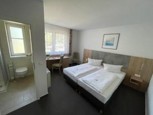 Schlafzimmer mit einem Bett, einem Schreibtisch und einem Tisch in der Unterkunft Hotel Garni Meeresblick in Glowe