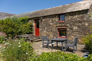 a stone cottage with a table and chairs in front of it at Delfryn Holiday Cottages in Solva