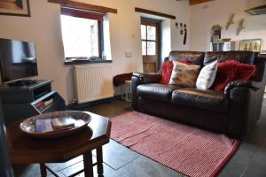 a living room with a leather couch and a table at Delfryn Holiday Cottages in Solva