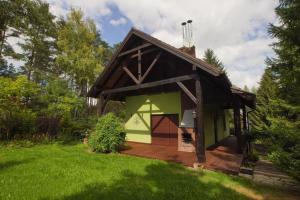 Kamińsko的住宿－Kamińsko by Latowisko - Puszcza Zielonka，一座绿色的小建筑,在院子里设有甲板