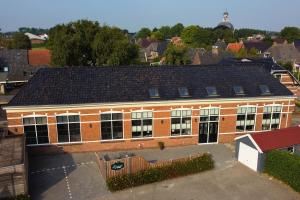 a large brick building with a lot of windows at Panta Rhei - Logement de 12e stad in Berlikum