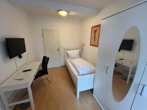 Habitación pequeña con cama, escritorio y ordenador. en Pension Donau, en Hannover