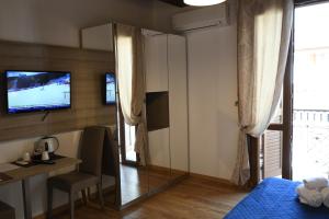 una camera da letto con specchio, scrivania e TV di Double B Maison De Charme ad Alghero