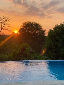 a sunset over a swimming pool with the sun setting at AFRA Reserva Natural in Santa Marta