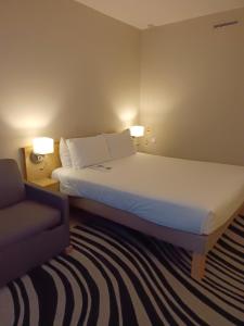 um quarto de hotel com uma cama e uma cadeira em Novotel Manchester West em Worsley