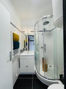 La salle de bains blanche est pourvue d'une douche et d'un lavabo. dans l'établissement La Brise Marine, à Calais