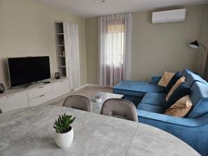 ein Wohnzimmer mit einem blauen Sofa und einem Tisch in der Unterkunft ANTRI Namai - Apartamentai Birštone in Birštonas