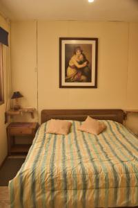 a bedroom with a bed with a painting on the wall at Coñaripe alojamiento in Panguipulli