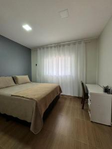 um quarto com uma cama, uma secretária e uma janela em Casa Amanhecer do Sol em Alto Paraíso de Goiás