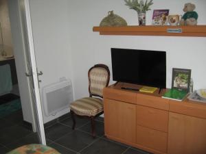Habitación con tocador, TV y silla. en Helen's Home en Bergerac