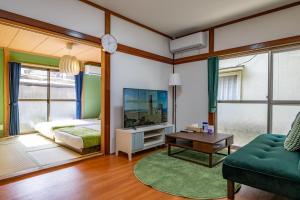 a living room with a green couch and a tv at Satorie Beppu in Beppu