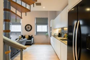 Livestay 3-Bed Loft Apartments in the Heart of Manchester في مانشستر: مطبخ وغرفة معيشة مع ثلاجة سوداء