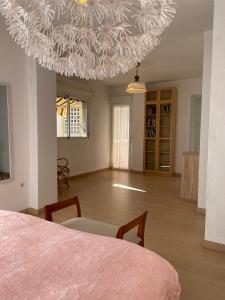 Habitación con cama, mesa y lámpara de araña. en H&H Suite El Santisimo, en Granada