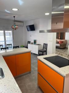 eine Küche mit orangefarbenen Schränken und ein Wohnzimmer in der Unterkunft H&H Suite El Santisimo in Granada