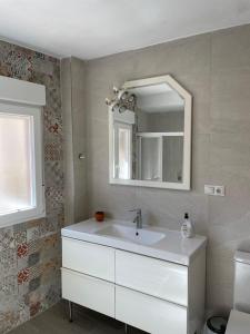 ein Badezimmer mit einem weißen Waschbecken und einem Spiegel in der Unterkunft H&H Suite El Santisimo in Granada