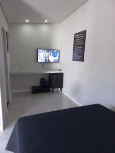 ein Schlafzimmer mit einem TV an einer weißen Wand in der Unterkunft Linda edícula a 80 m da Praia de Itapuã in Salvador