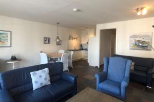 Una sala de estar con un sofá y sillas y una cocina. en Villa Duindoorn 2.302, en Cadzand