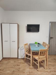 ein Esszimmer mit einem Tisch, Stühlen und einem TV in der Unterkunft Gościnna Hacjenda in Radwanice