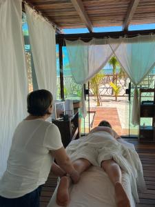 a woman standing next to a man laying on a bed at Camozen Resort & Spa in Camocim