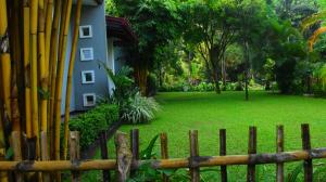 a fence in front of a house with a green yard at Leel’s Safari Cottage in Udawalawe