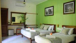 um quarto com 2 camas, um sofá e um espelho em Leel’s Safari Cottage em Udawalawe