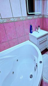 een badkamer met een wit bad en een wastafel bij Apartman Sekulić in Doboj