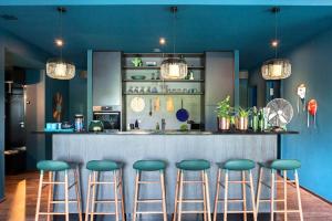 a bar with blue walls and green stools at NOMADS by Suite030 high class apartments, 1-2 bedrooms in Berlin