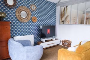 uma sala de estar com uma televisão e uma cadeira em Le Cocon des Layes em Les Essarts-le-Roi
