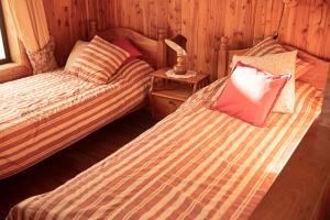 a bedroom with two beds and a table with a lamp at Coñaripe alojamiento in Panguipulli