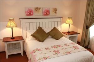ein Schlafzimmer mit einem Bett mit zwei Lampen an Tischen in der Unterkunft The Rose Cottage B&B in Dullstroom