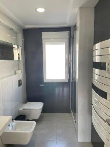a bathroom with a toilet and a sink and a window at H&H Casa en centro de Granada in Granada