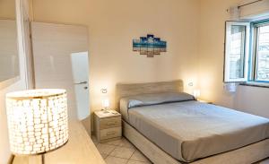 a bedroom with a bed and a lamp and a window at La Casa del Panza con vista mare in Isola del Giglio