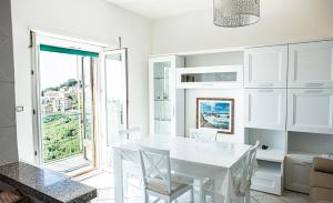 a white dining room with a white table and a window at La Casa del Panza con vista mare in Isola del Giglio