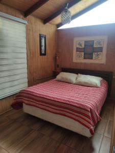 a bedroom with a bed with a red blanket at Las 2 Golondrinas in El Quisco