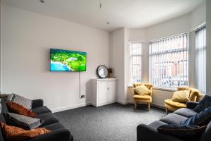 a living room with couches and a tv on a wall at Harmony House: Shared Spaces Room 3 in Manchester