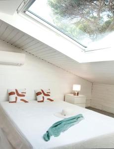 a bedroom with a white bed with a window at Chalet Californien, piscine privée, plage 5 mn ! in Gassin