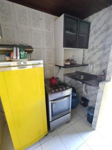 uma pequena cozinha com um fogão e uma porta amarela em Casa 3/4 Guarajuba BA em Camaçari