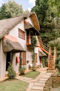 a house with a thatched roof and a staircase at Thatchings Guest House in Nottingham Road