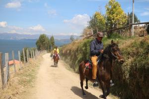two people riding horses down a dirt road at HOTEL TOTA ELISEO PLAYA BLANCA LAGO DE TOTA in Tota