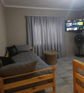 a bedroom with a bed and a table and a television at OR Tambo Rudman B self-Catering Home L2 in Boksburg