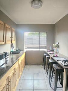 a kitchen with wooden cabinets and a table with stools at OR Tambo Rudman B self-Catering Home L2 in Boksburg