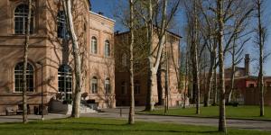 a large brick building with trees in front of it at Grand Hotel di Parma in Parma