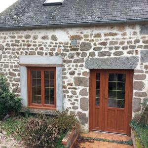 een stenen huis met twee deuren en twee ramen bij gîte le petit roussel in Putanges