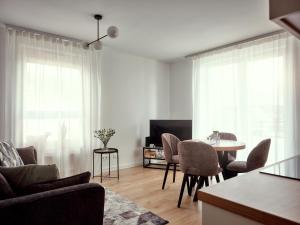 a living room with a table and chairs and a television at A&W Apartament Zatoka Zwycięstwa - Rokosowo in Koszalin